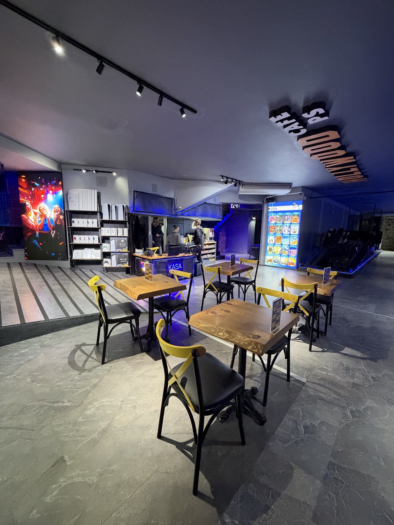 Kafe masaları ve oyun istasyonlarının bulunduğu salon